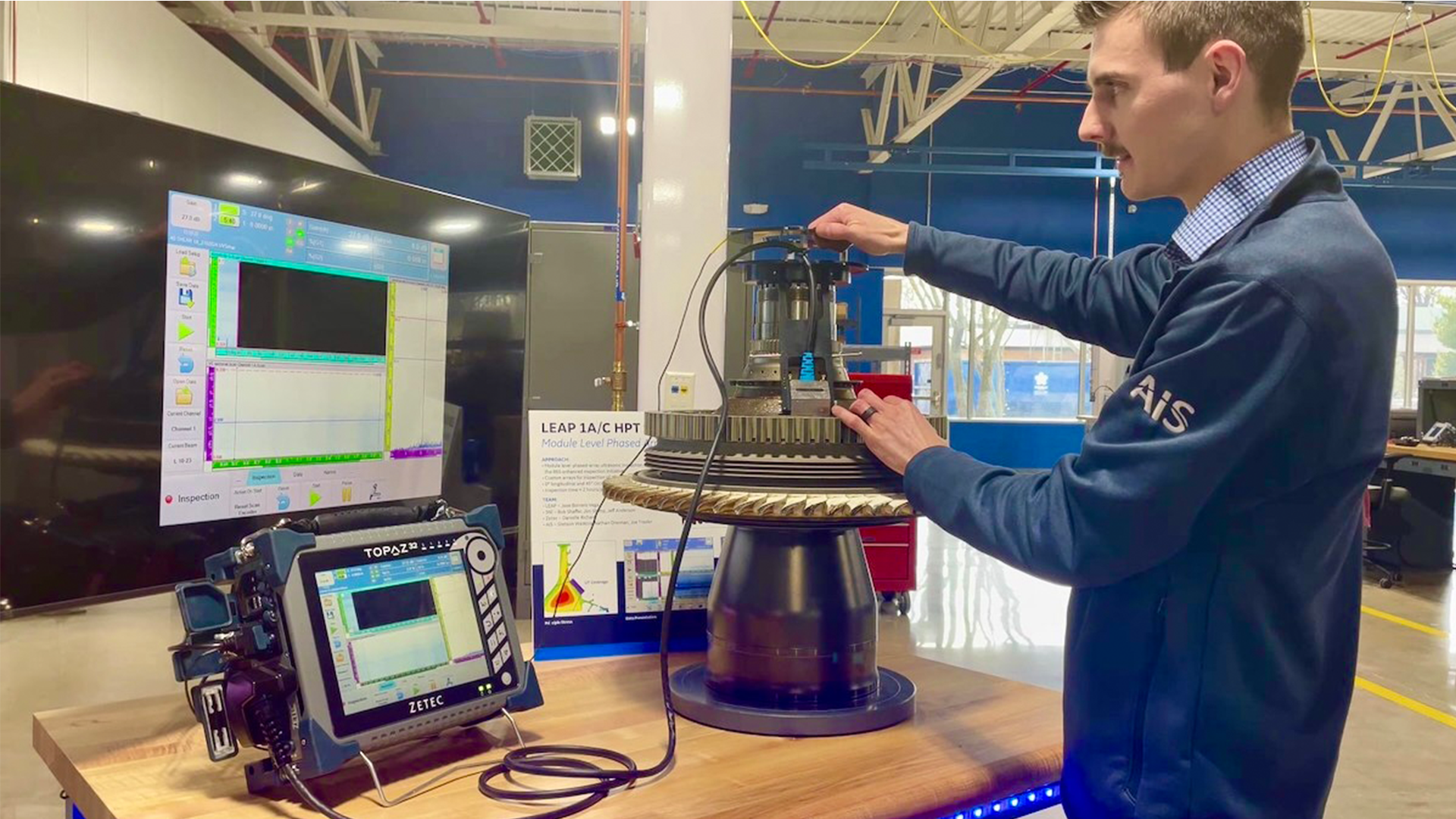 Nick Van Zandt, an AIS Lead Engineer, studies the scan of an engine part submerged in an ultrasonic immersion tank