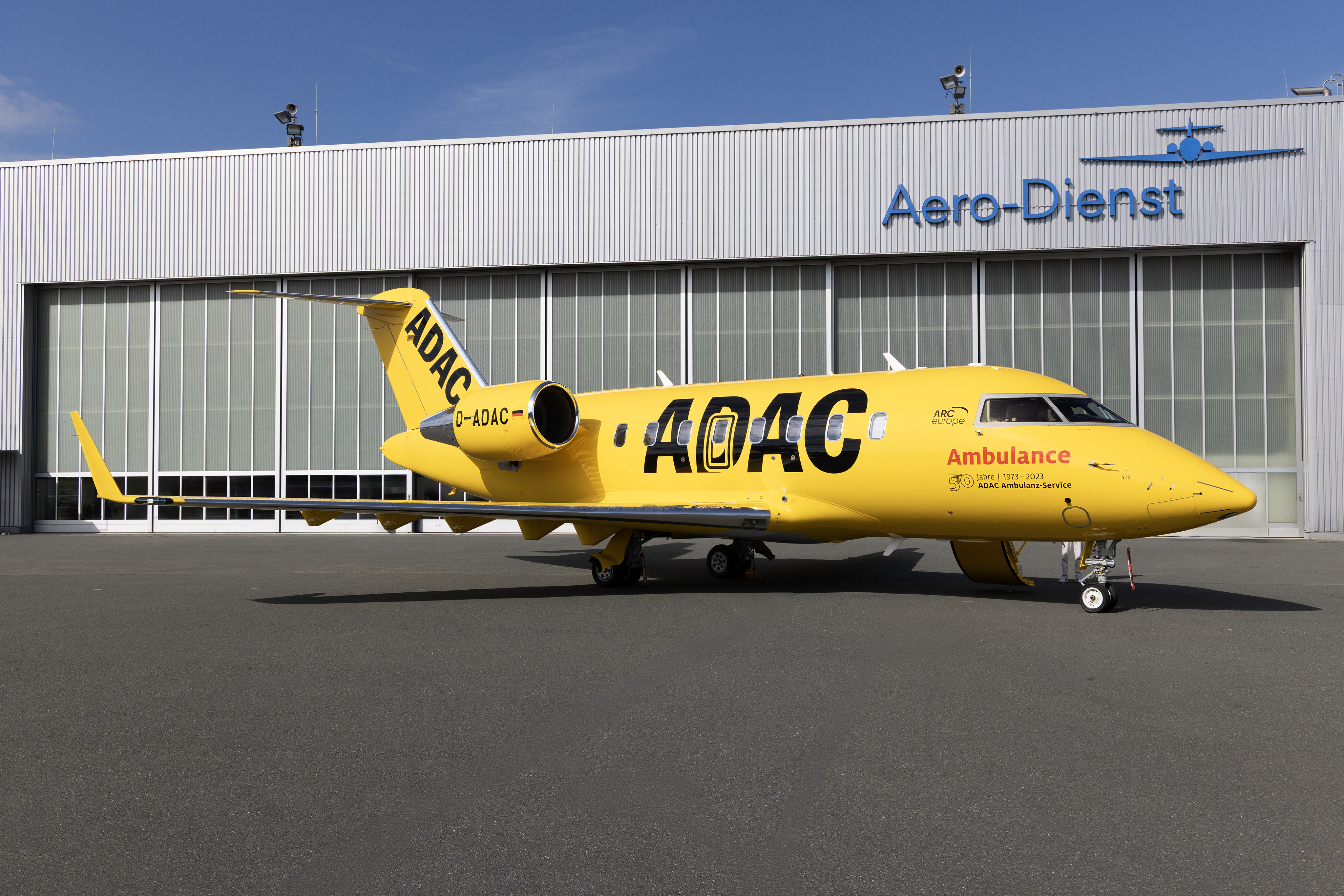 Bright yellow ADAC air ambulance jet, registration D-ADAC, parked on the apron...