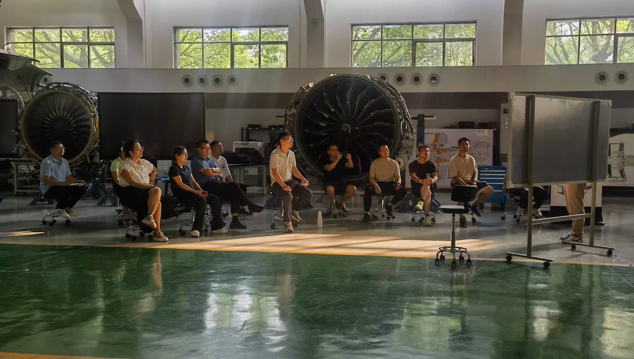 A group of engineers participate in training in a large room full of example engines, part of the AEMTC, China’s first civil aviation engine vocational training institution of its kind
