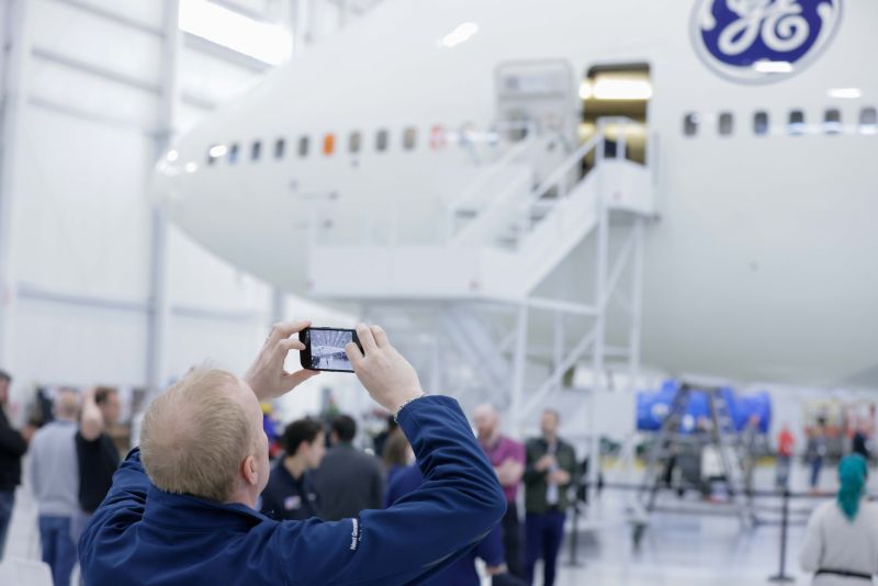 nose in hangar, employee snapping cellphone shot in foreground