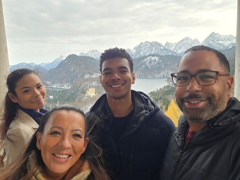 Family of four taking a selfie in front of mountains and a lake