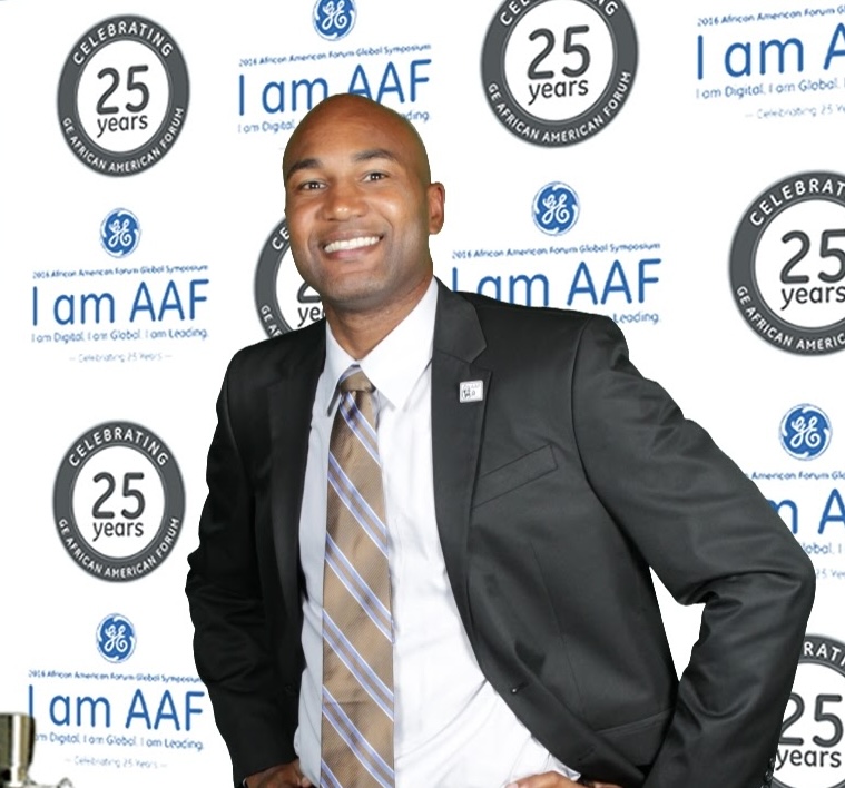 Man in a suit standing in front of a picture wall celebrating 25 years of AAF