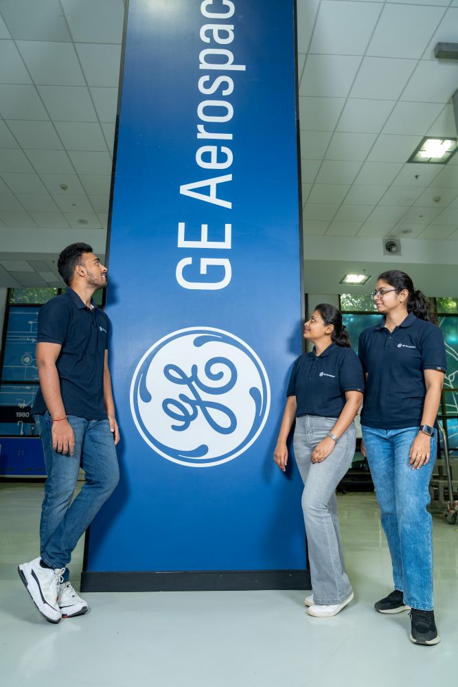 The three engineers looking at a column with the GE Aerospace logo on it