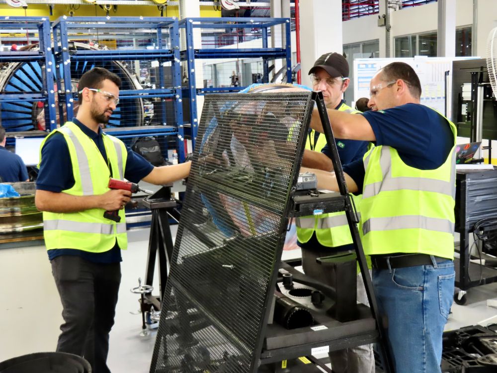 3 men in neon vests working on a piece of machinery