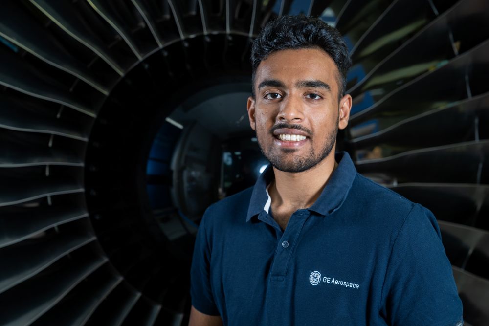Man in a dark blue GE Aerospace polo in front of an engine