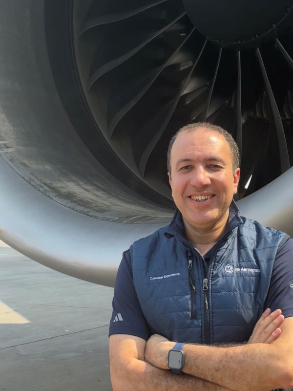 Middle aged man posing in front of a jet engine