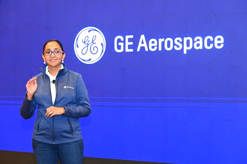 Woman standing in front of a GE Aerospace logo on a blue background