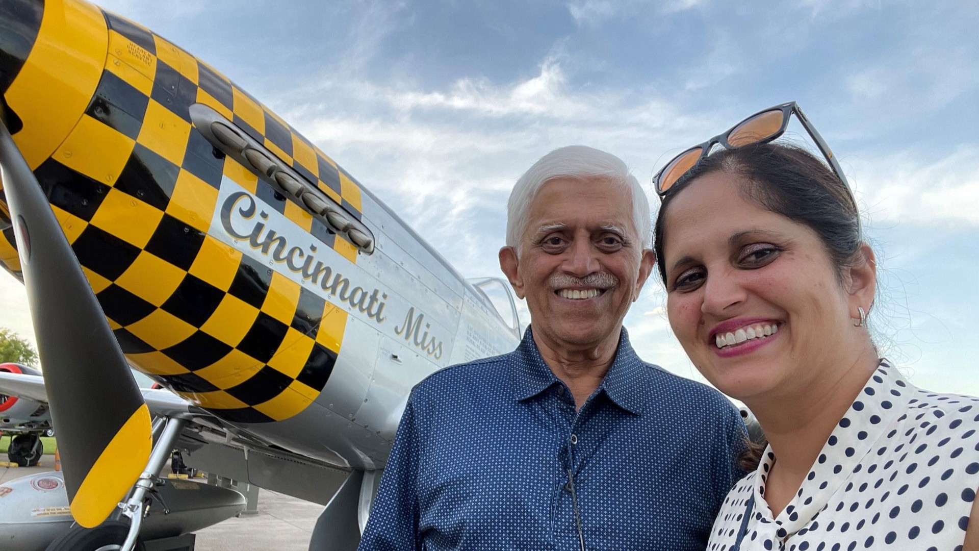 Man and woman standing next to a black and yellow checkered plane