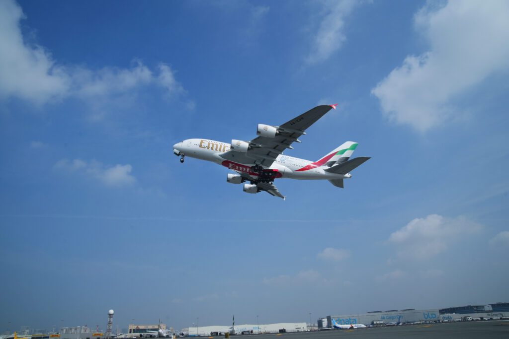 Image of Emirates aircraft A380 flying through blue skies. 